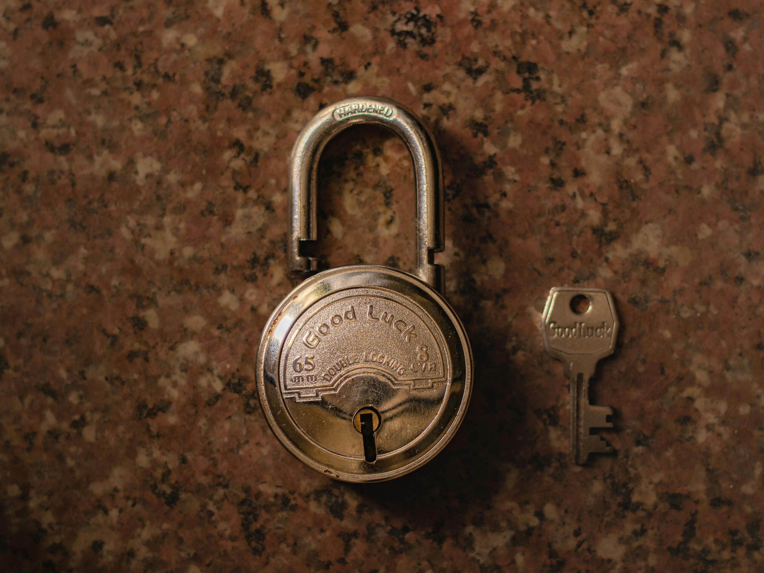 Keep your data safe on Lavish Young Creators A close-up view of a vintage padlock with its key on a stone surface.